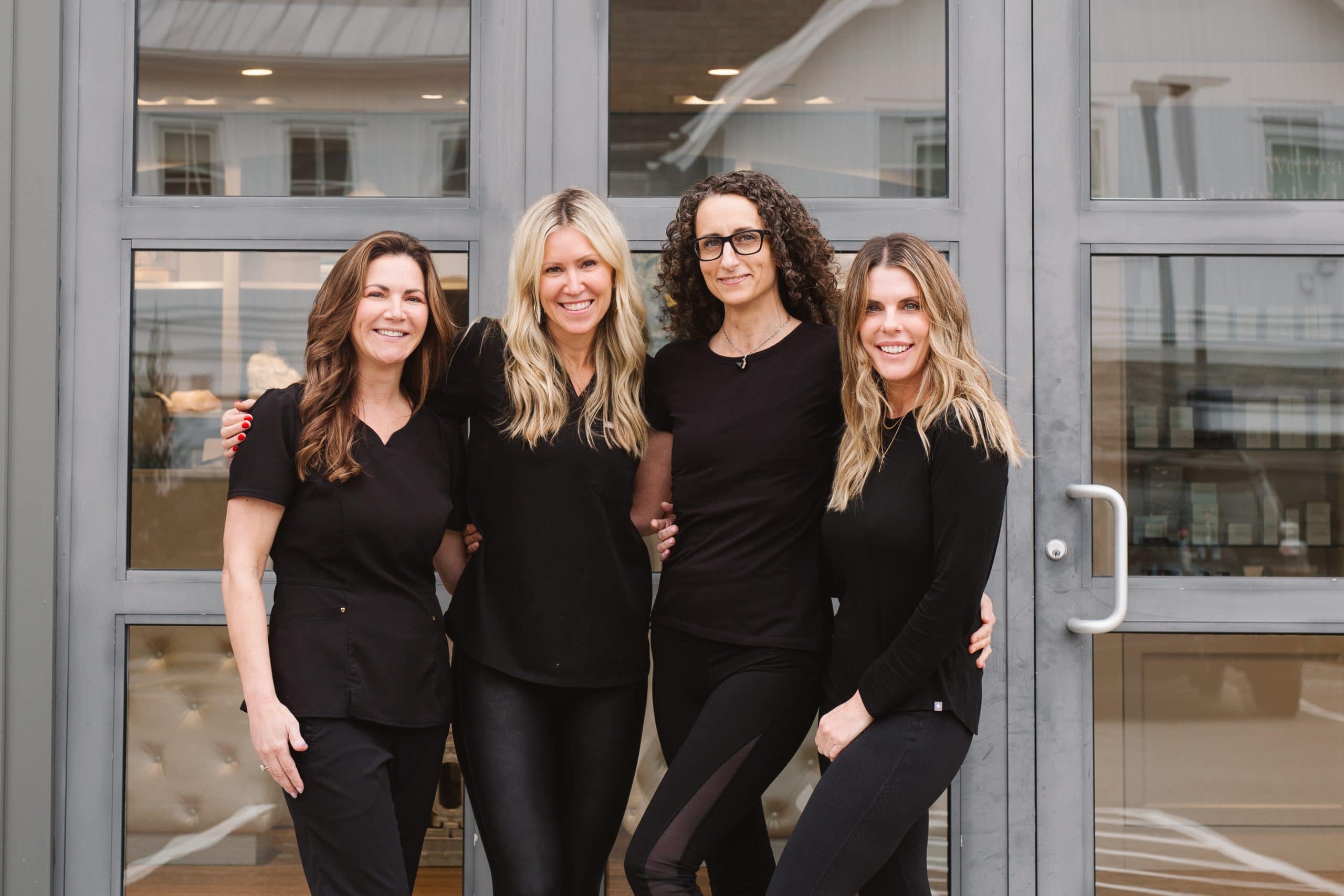 4 women in all black standing in front of new beauty and wellness