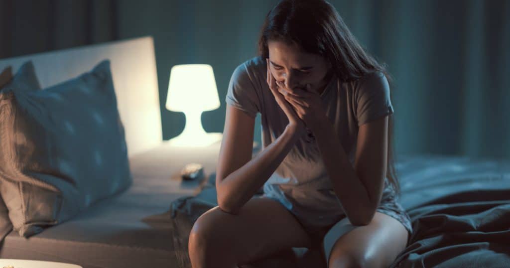 A woman sitting on her bed, worried regarding her TMJ