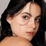 a close-up portrait of a young woman with long dark hair and clear, glowing skin.