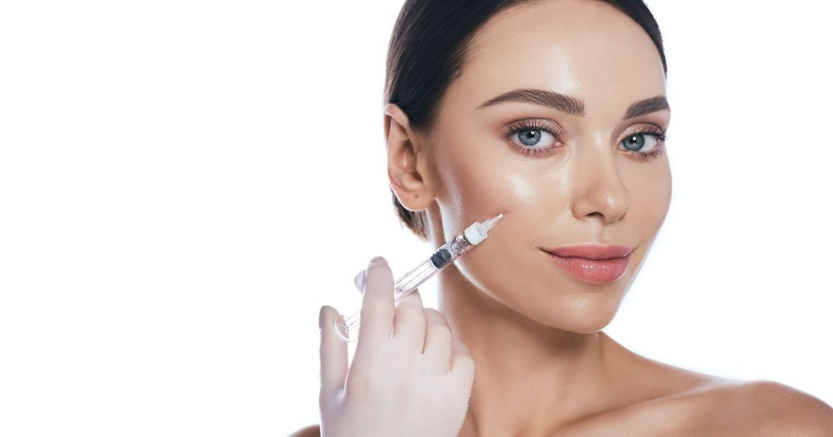 Woman receiving a dermal filler injection to enhance facial contours and restore volume.